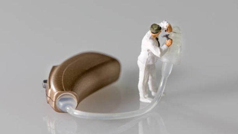 miniature audiologist adapting hearing aid